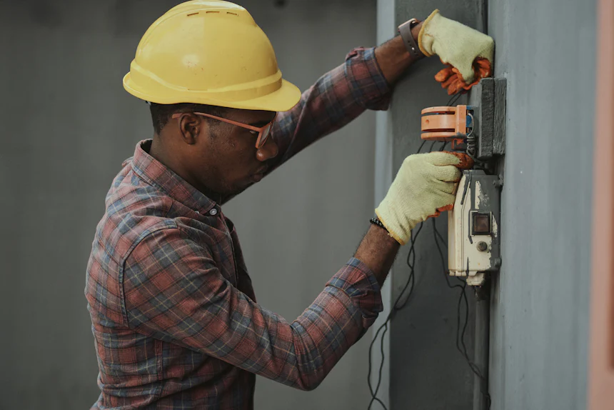 Technician in a hard hat working on an electrical panel